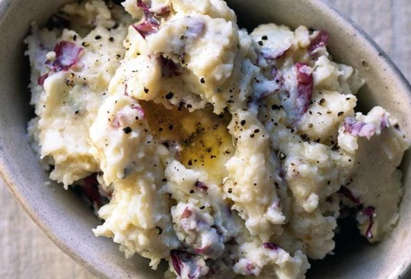 A baking dish filled with mashed potatoes that are sprinkled with black pepper