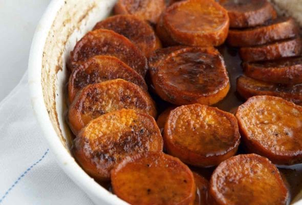 A white baking dish filled with slices of cooked sweet potato