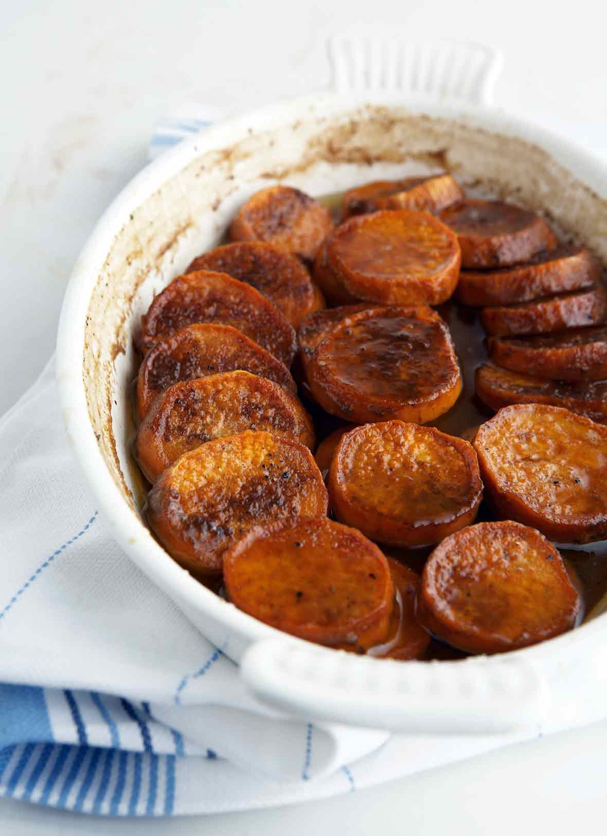 A white baking dish filled with slices of cooked sweet potato