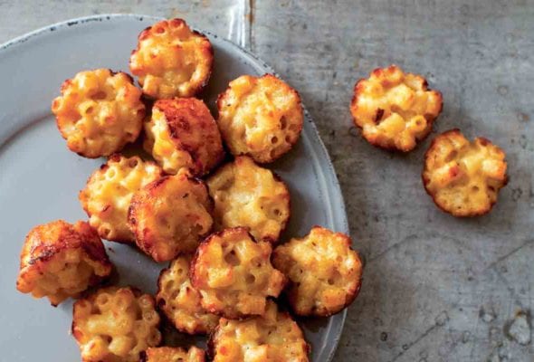 A grey plate half-filled with mac and cheese canapes, with a few resting beside the plate