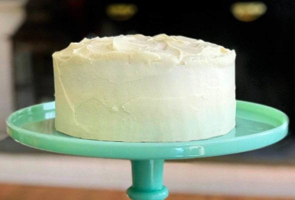 A pumpkin cake with maple-cream cheese frosting on a teal cake stand.