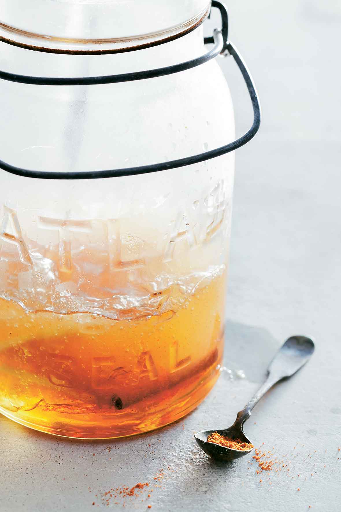 Glass jar with a cold and flu drink with a cinnamon stick, a spoon with ginger