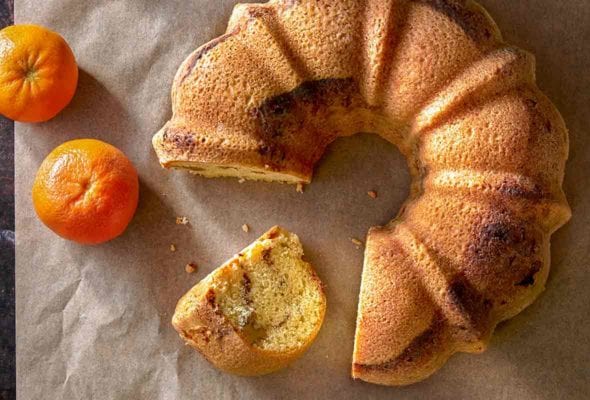 Zingerman's Sour cream coffee cake Bundt with a slice cut out and oranges on parchment paper