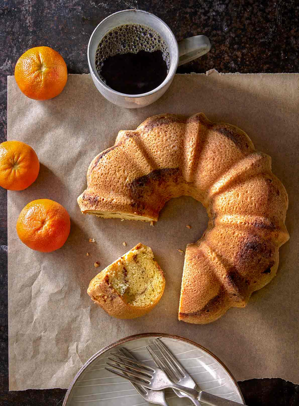Zingerman's Sour cream coffee cake Bundt with a slice cut out and oranges on parchment paper