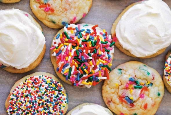 8 birthday cake cookies covered in white frosting and colored sprinkles