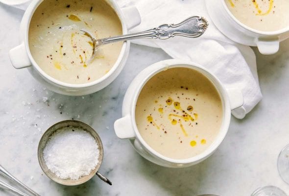 Three bowls of fennel and potato soup, topped with cracked pepper and a dribble of olive oil, spoons on the side
