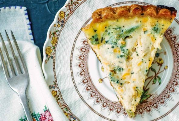 A plate with a slice of broccoli Cheddar quiche