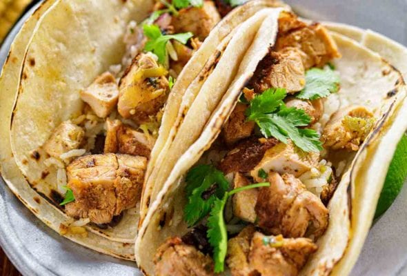 Wood bowl with tequila-lime chicken tacos, charred limes, radishes, sour cream
