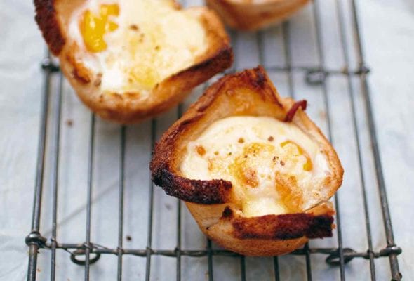 Three croque madame muffins on a wire rack, set over parchment paper.