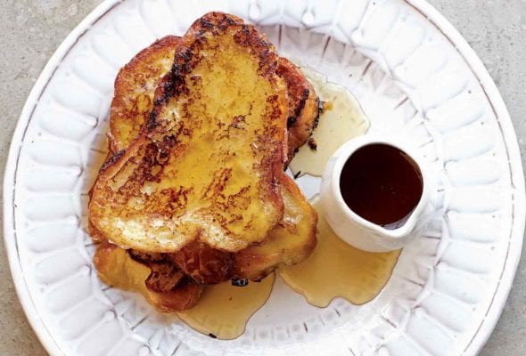 Three slices of French toast drizzled with Earl Grey syrup on a white plate.