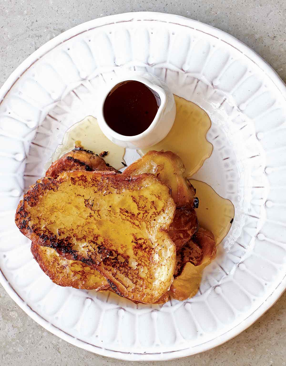Three slices of French toast drizzled with Earl Grey syrup on a white plate.