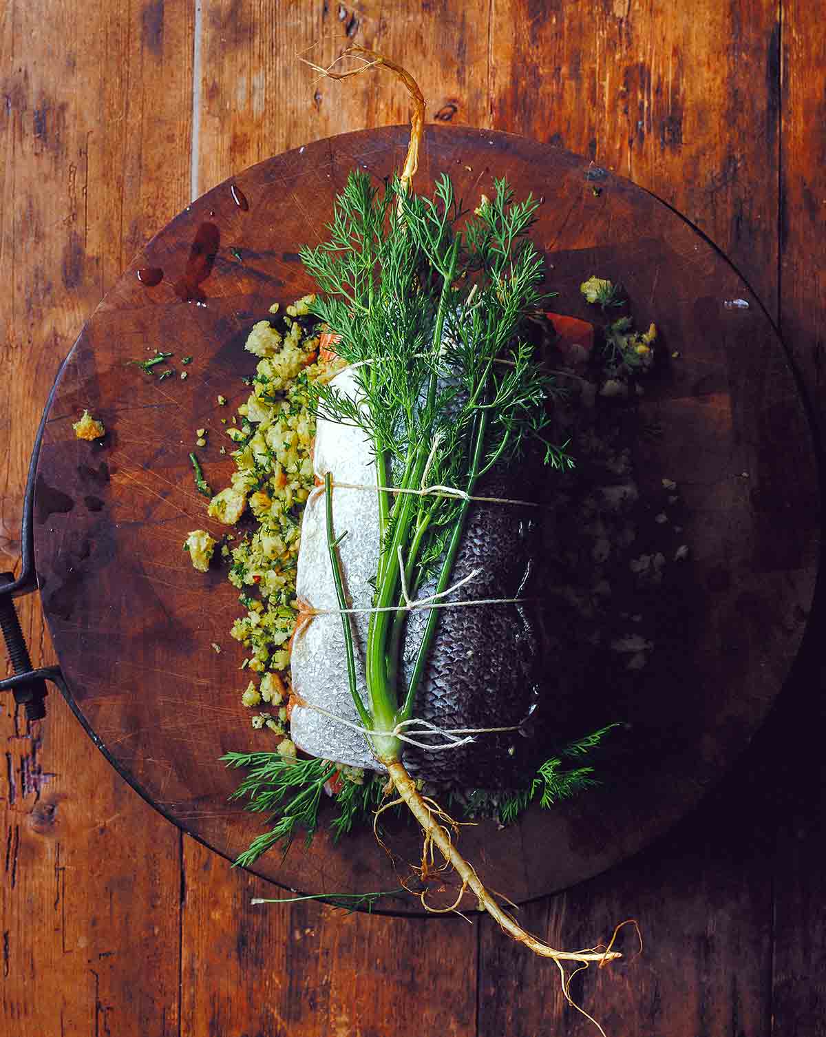 A whole herb stuffed baked salmon filled with bread crumbs and herbs and tied with kitchen twine.