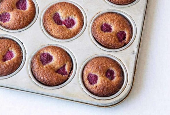 A muffin tin filled with raspberry-studded financiers.
