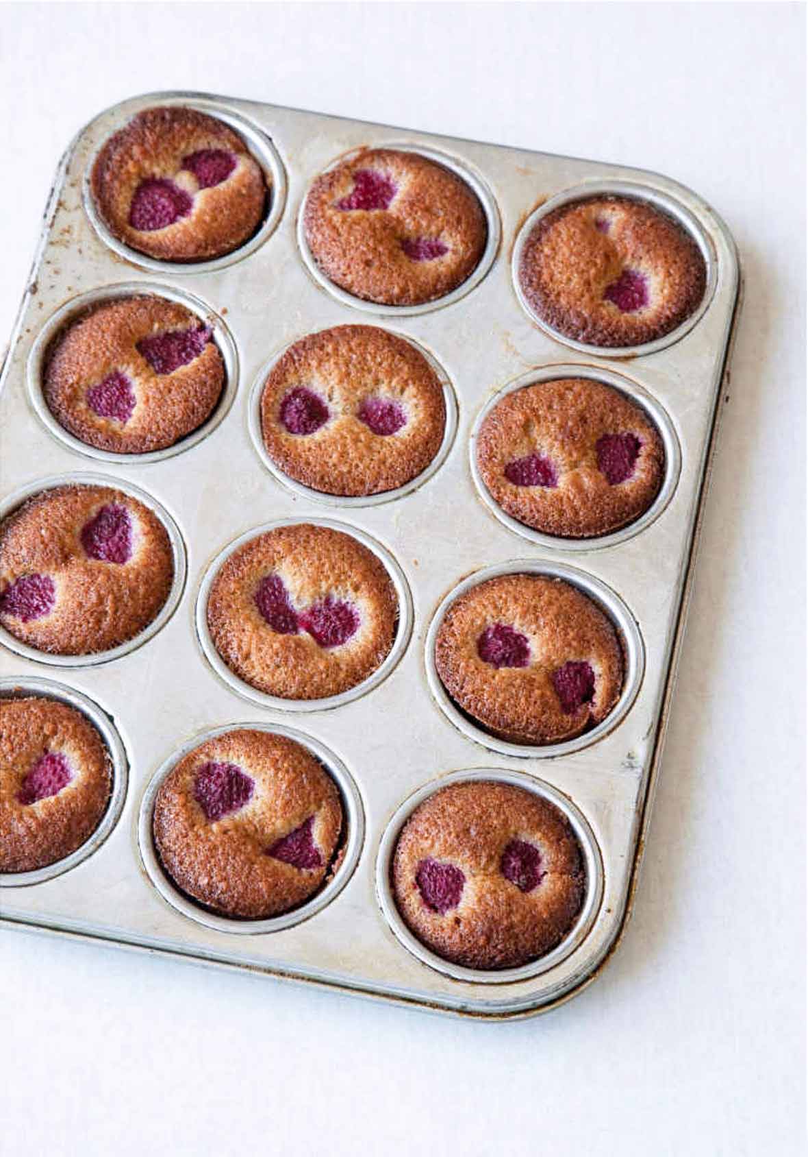 A muffin tin filled with raspberry-studded financiers.