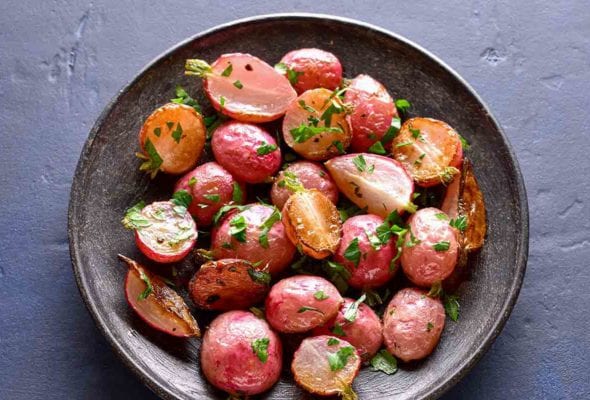 A grey bowl filled with roasted radishes, sprinkled with thyme.