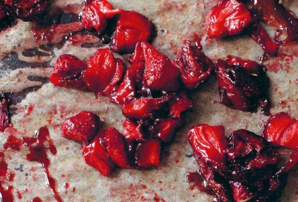 Chunks of roasted strawberries on a sheet of parchment.