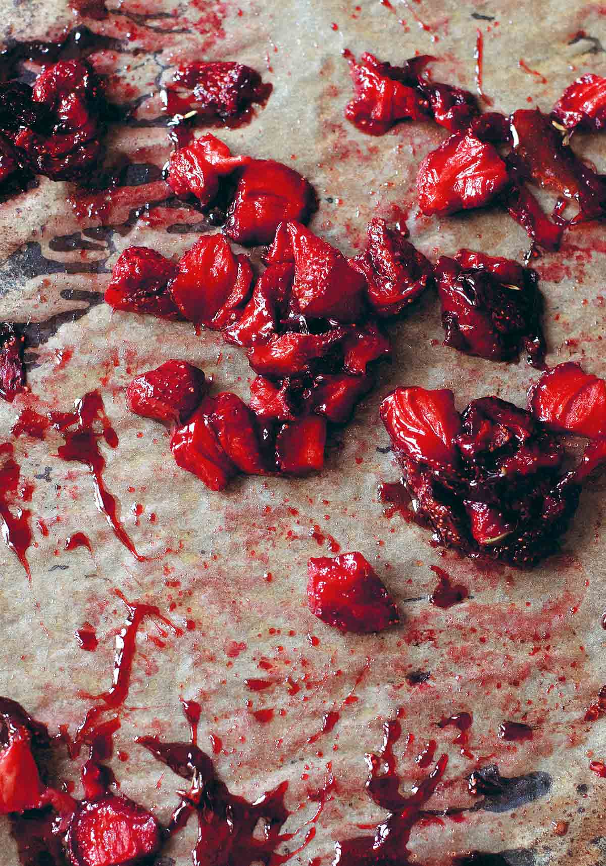 Chunks of roasted strawberries on a sheet of parchment.