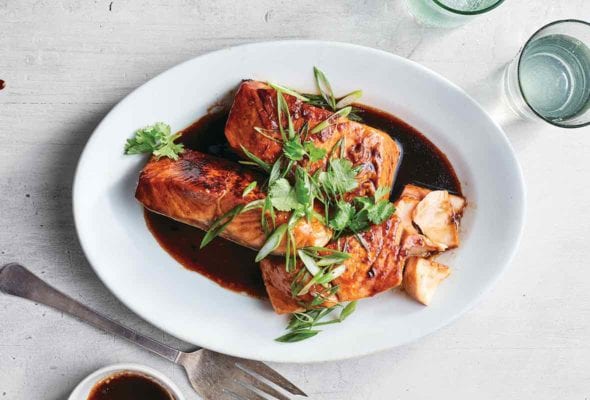 Pressure cooker Vietnamese caramel salmon, sliced green onion, and soy sauce on a white plate