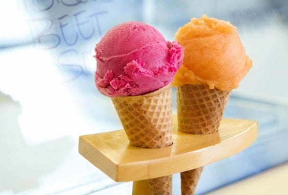Two sugar cones, one filled with a scoop of cantaloupe sorbet, the other with a scoop of hibiscus sorbet.