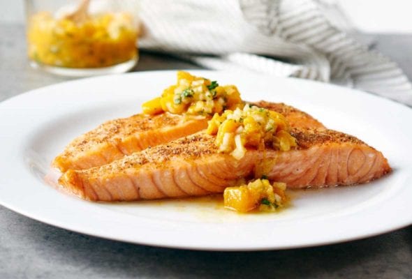 White plate with a fillet of Indian-spiced salmon with mango salsa on top