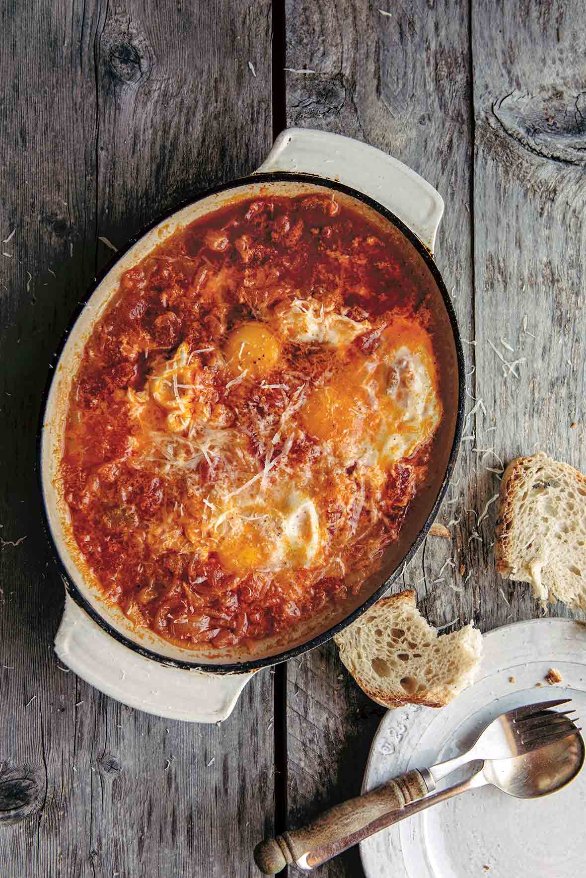 Casserole dish of acquacotta maremmana, a thick, slow-cooked stew of vegetables, poured over a slice of stale bread with poached eggs on top