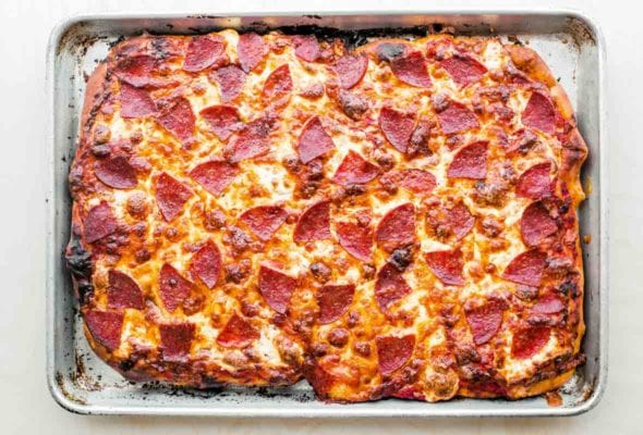 A sheet pan with pepperoni pan pizza, with cheese and pepperoni on top