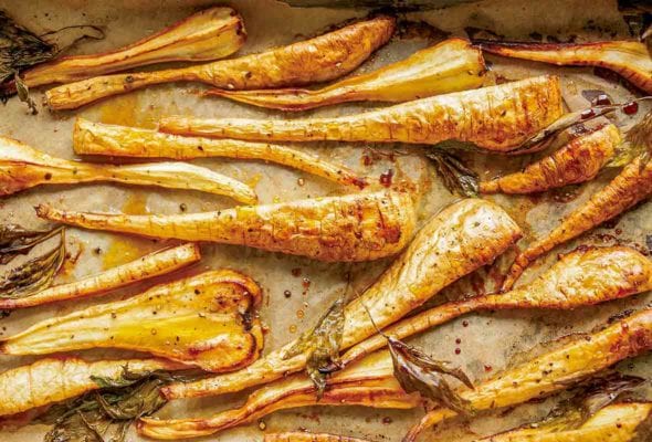 Sheet pan lined with parchment and sliced maple roasted parsnips