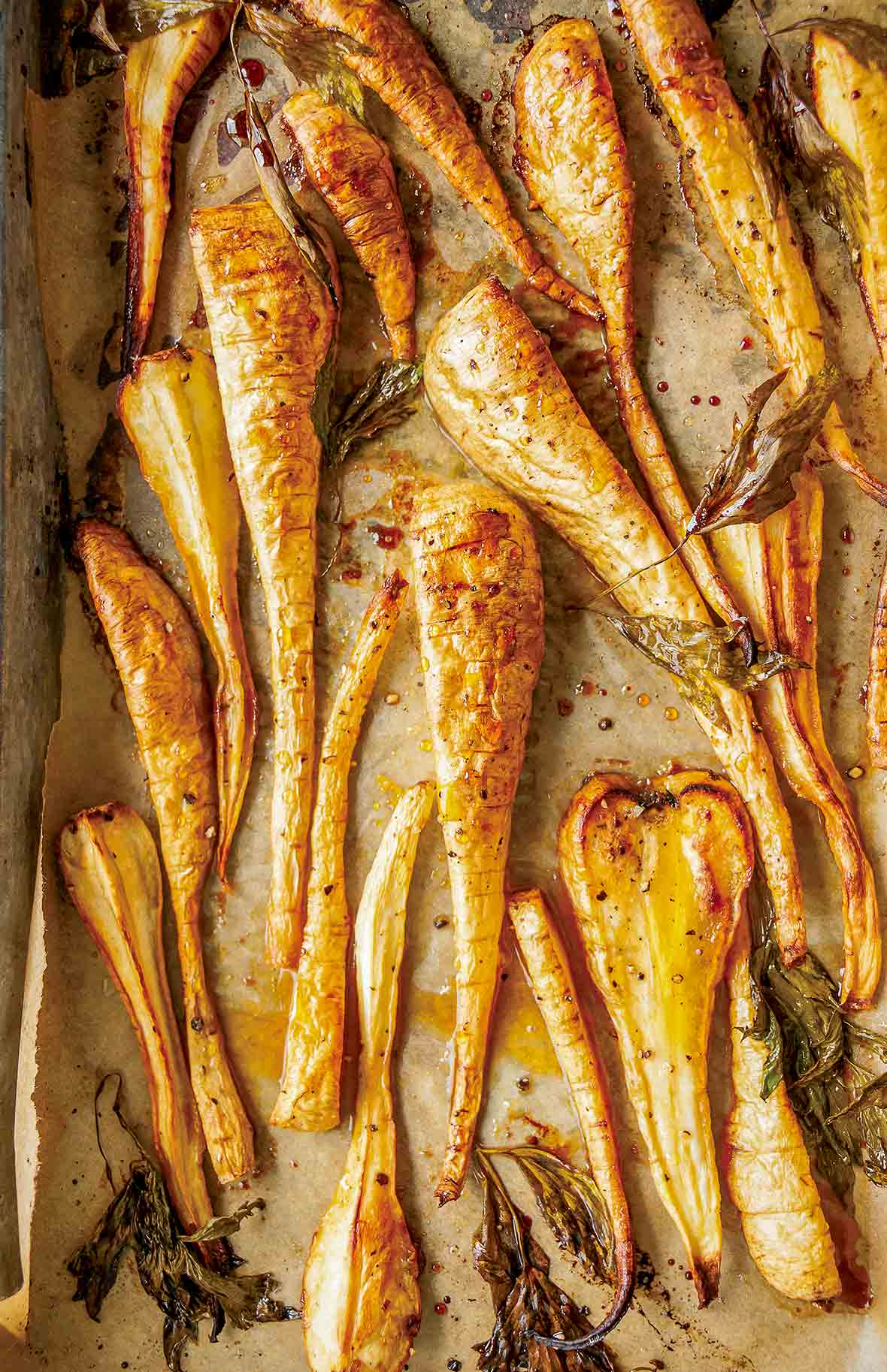Sheet pan lined with parchment and sliced maple roasted parsnips