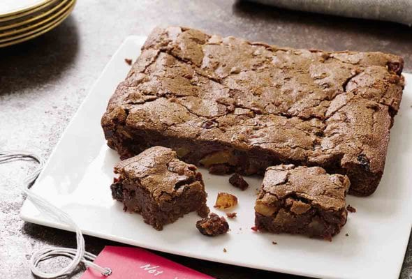A square white platter with fruitcake brownies--filled with dried fruit, chocolate, and rum