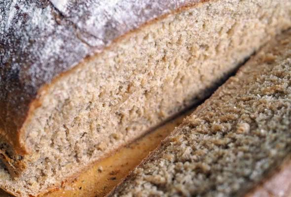 A cut-open loaf of multigrain bread made with a mix of rye, barley, oats, whole wheat flours, and molasses, and milk