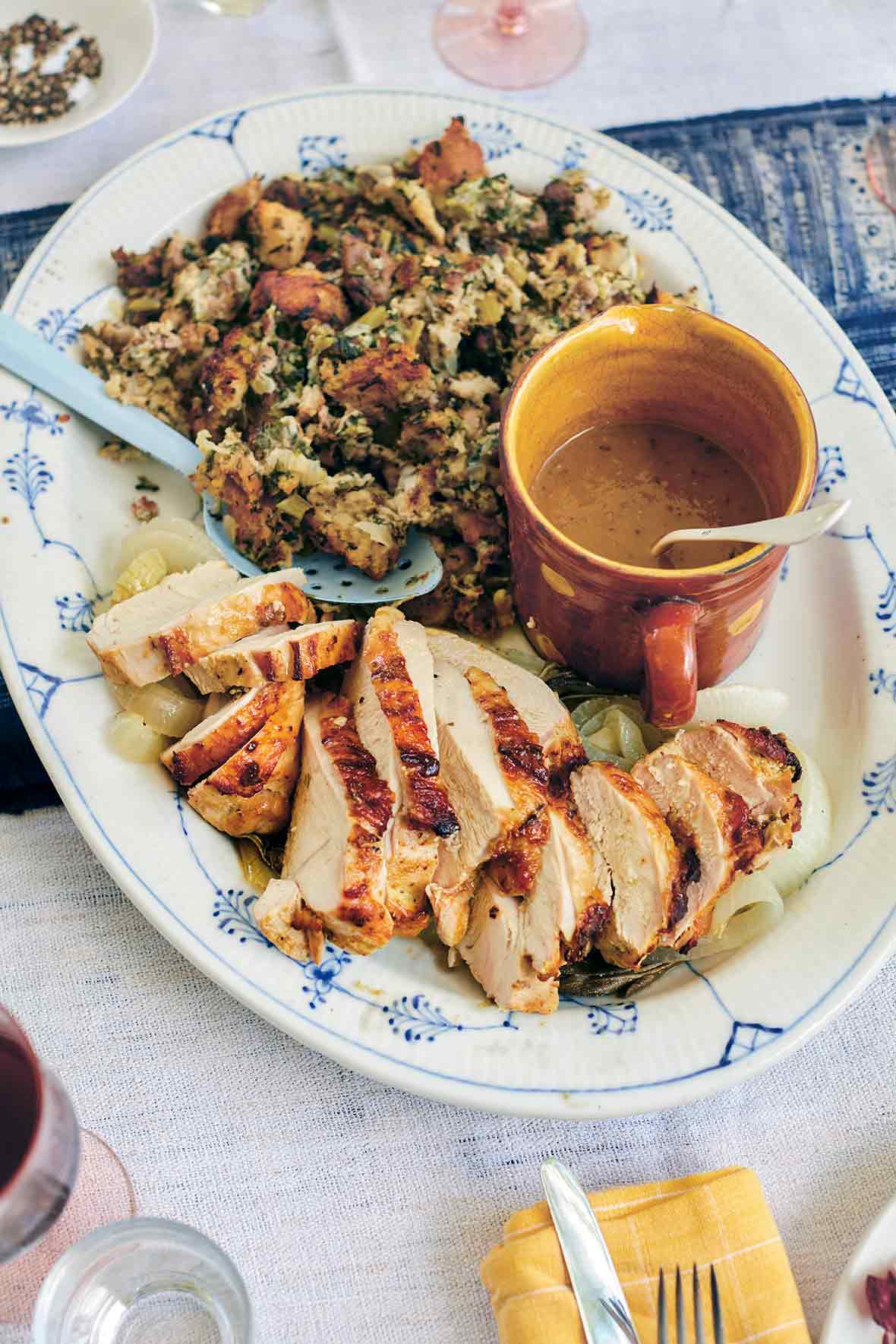 White and blue plate with sliced roast turkey breast with herbed stuffing and gravy