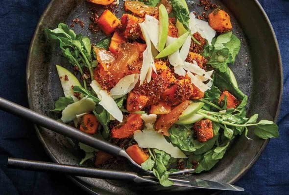 A pottery plate filled with roasted butternut squash and apple salad made with watercress, sweet apples, and topped with Parmesan