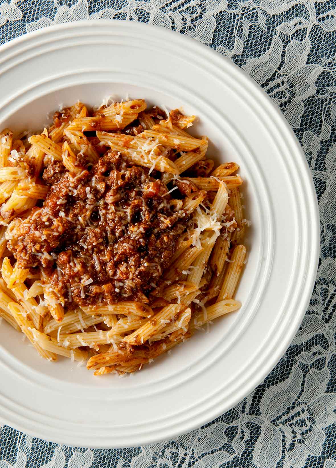 White bowl of venison Bolognese made with ground venison, carrots, onion, celery, mushrooms a top rigatoni