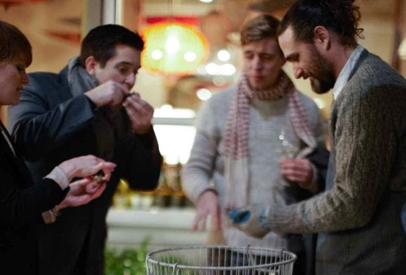 Four people eating raw oysters with mignonette sauce.