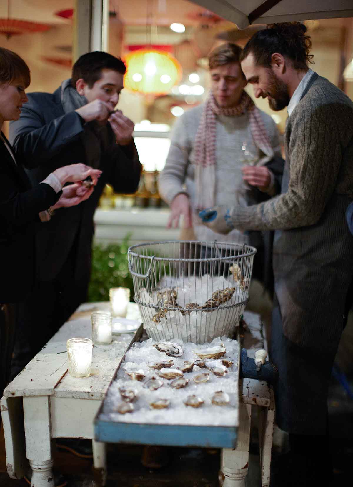 Four people eating raw oysters with mignonette sauce.