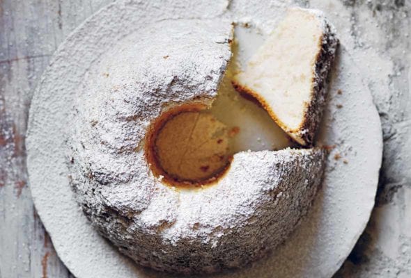 A vanilla angel food cake in Bundt form, with a slice on its side, all sprinkled with powdered sugar