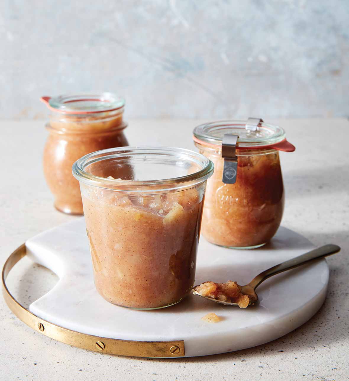 Three jars of slow cooker apple pear sauce on a white tray