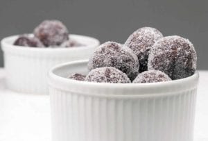 Two white ramekins with a pile of sugar-coated bourbon balls