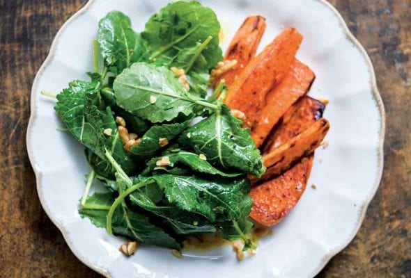 white plate of kale miso salad with roasted sweet potatoes on the side
