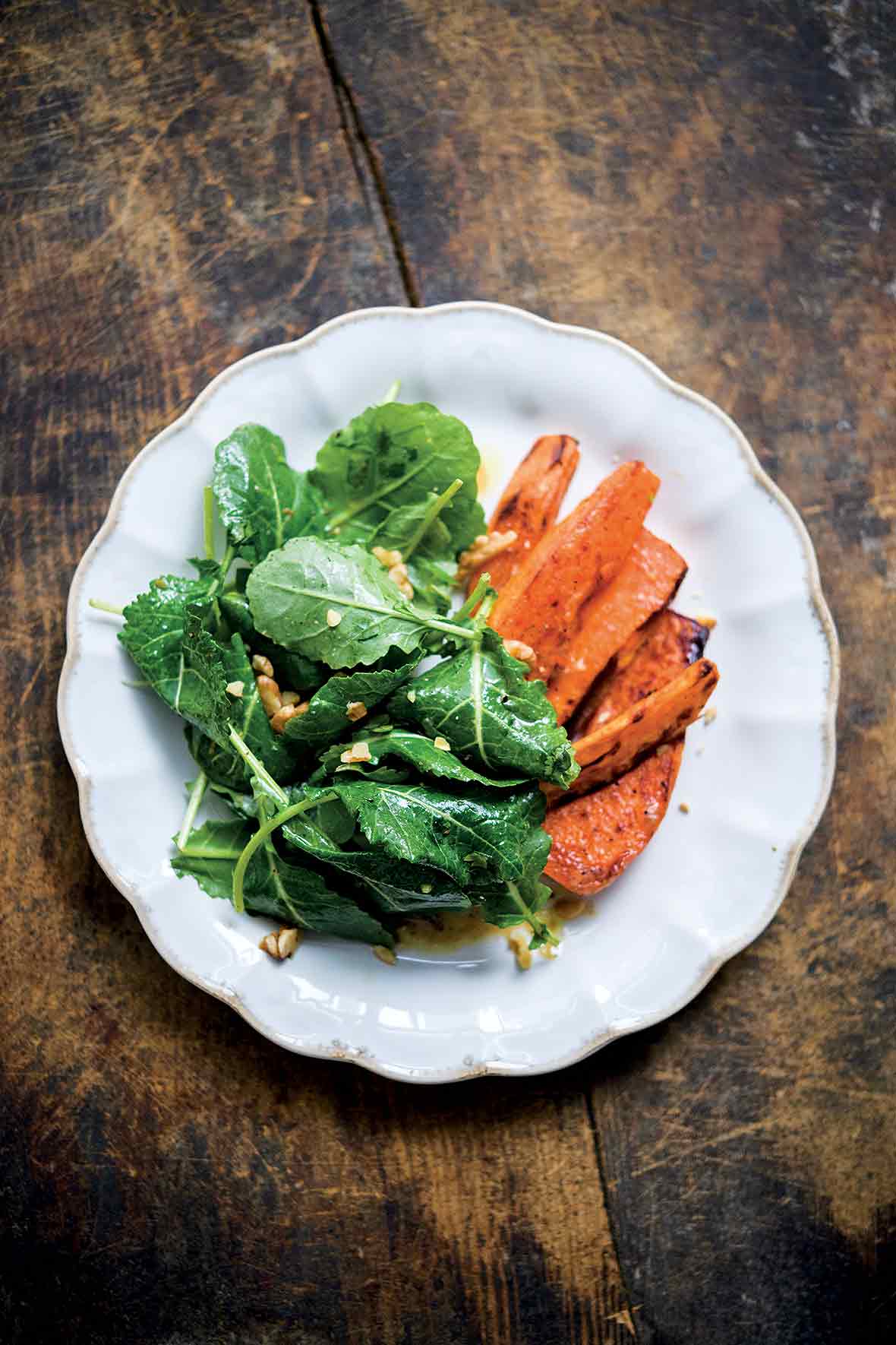 white plate of kale miso salad with roasted sweet potatoes on the side