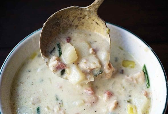 A bowl of creamy New England clam chowder with clams, potatoes, leeks, shallots, cream, and chives