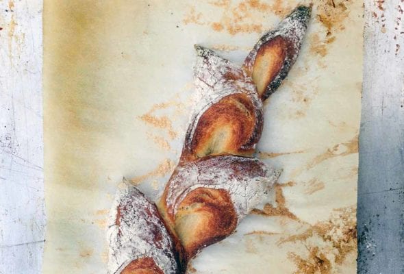 A baked pain d'epi on a piece of parchment paper.