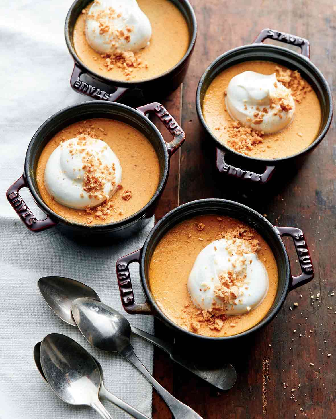 Four small crocks of pumpkin pots de creme--pumpkin pudding topped with crumbled cookie and whipped cream
