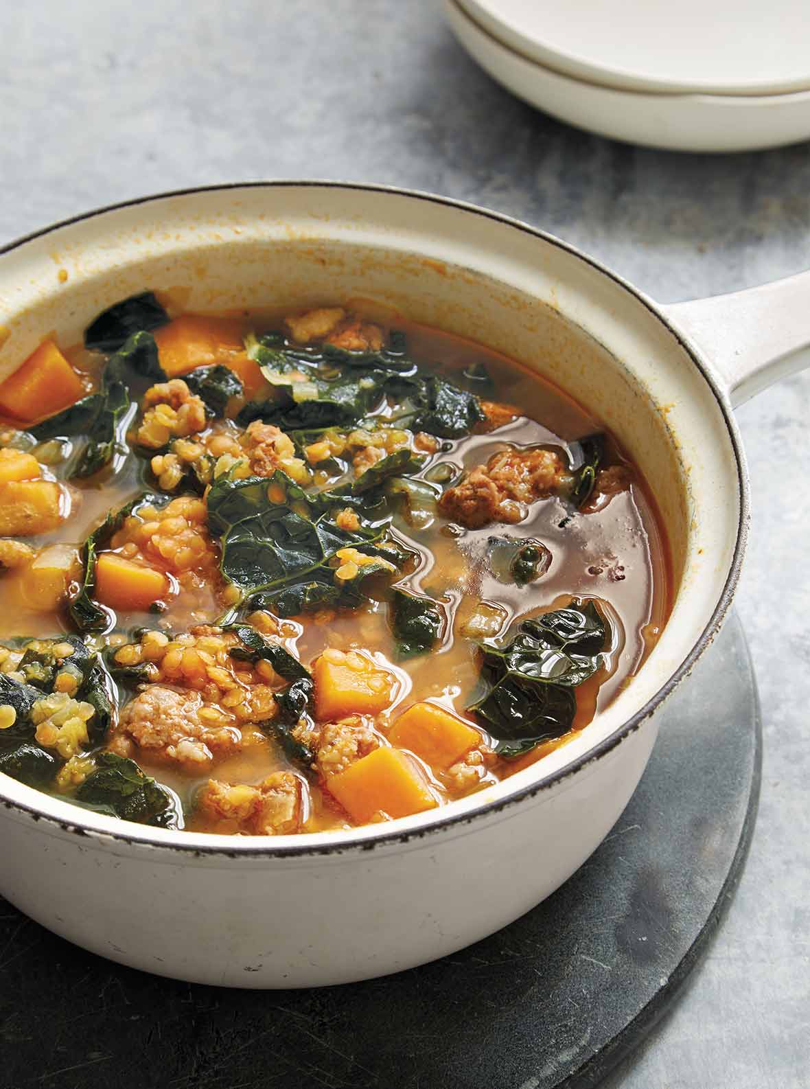 Bowl of red lentil soup with kale and chorizo, sweet potatoes, and onions