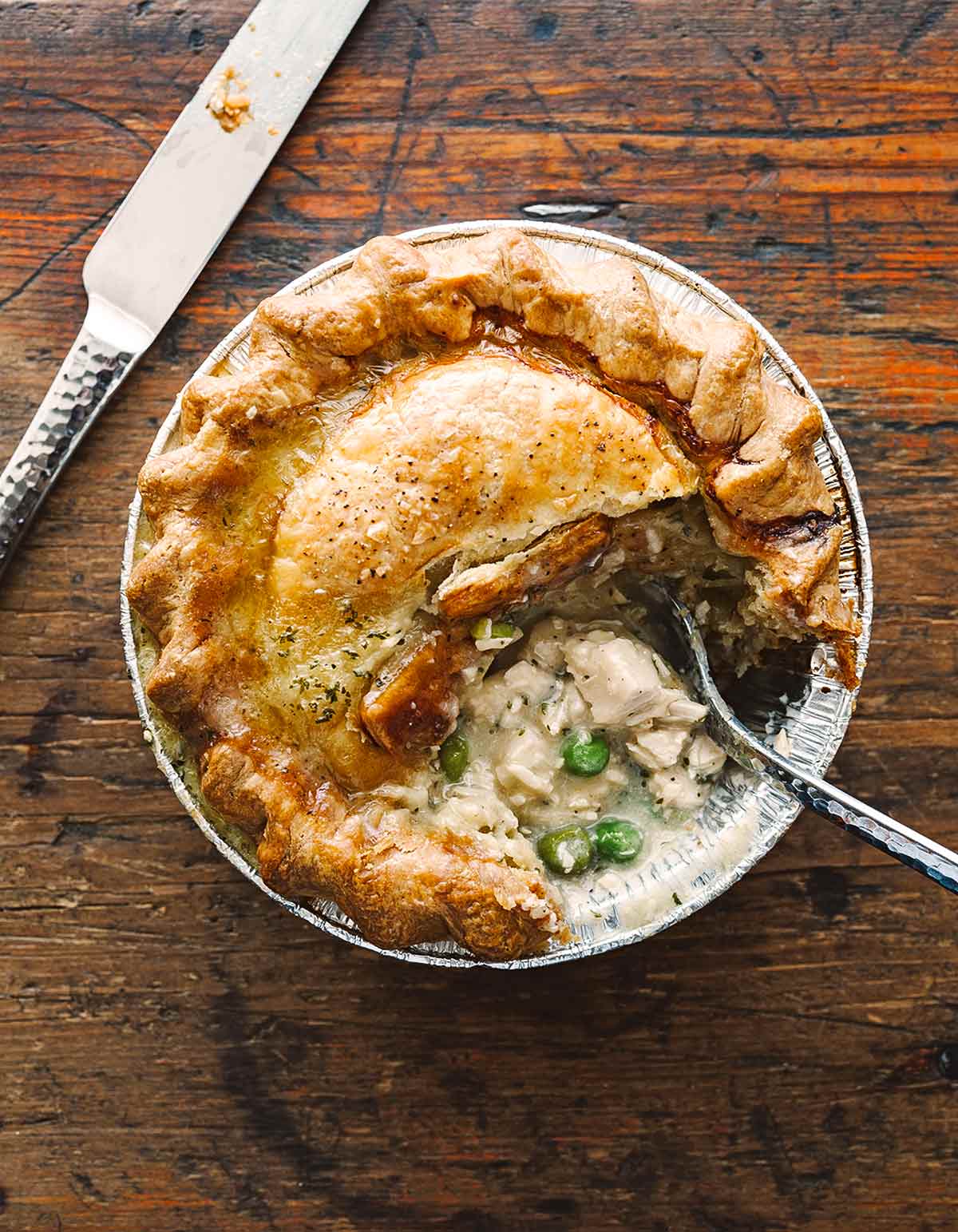 A mini homemade chicken pot pie with a flaky crust, chunks of white meat chicken, and peas