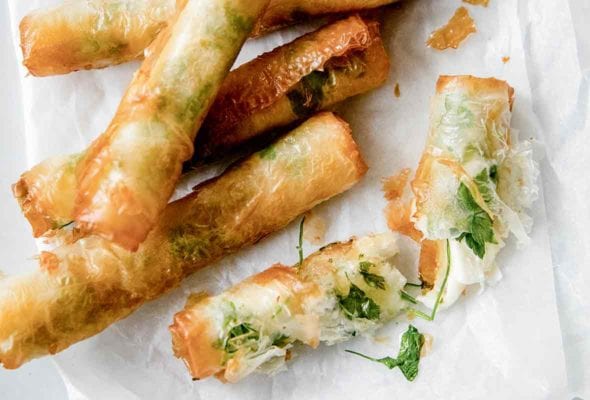 Seven crispy rakakat (Turkish cigars) on a parchment-lined white plate