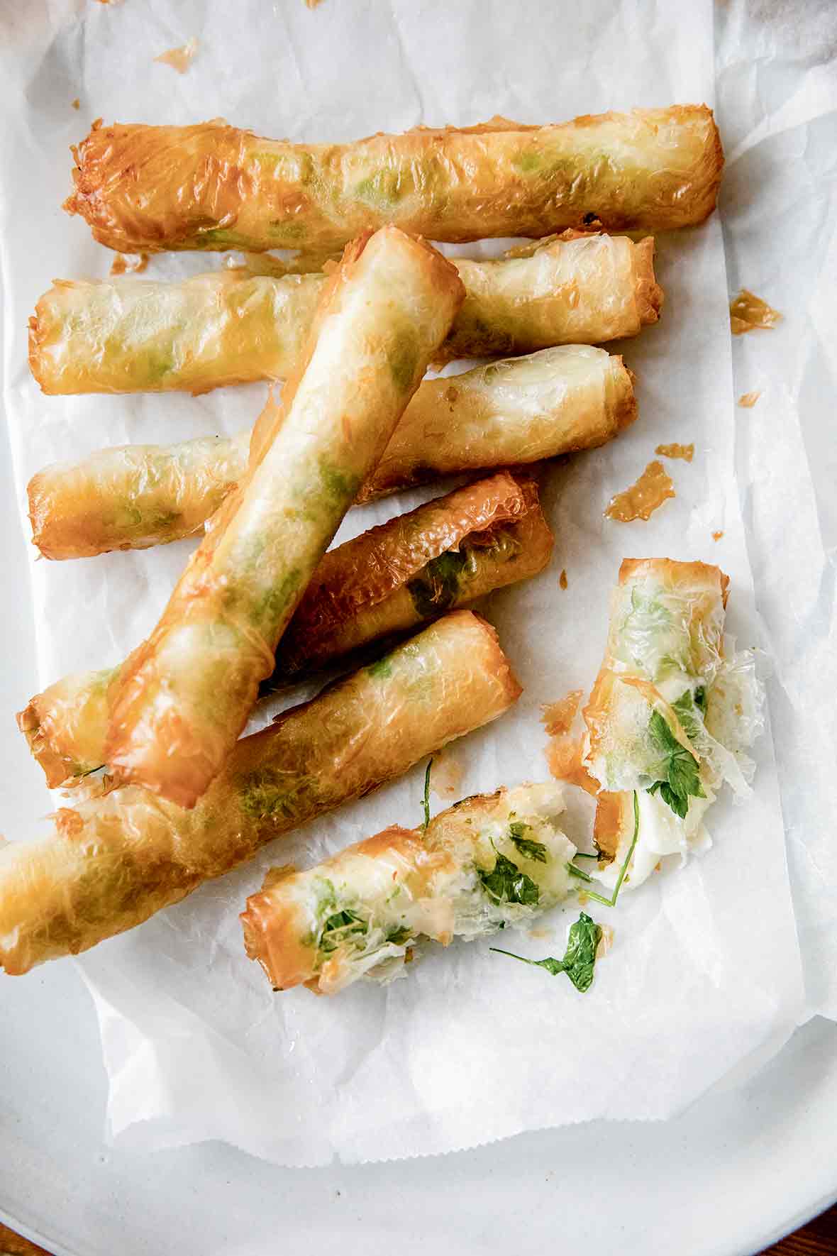 Seven crispy rakakat (Turkish cigars) on a parchment-lined white plate