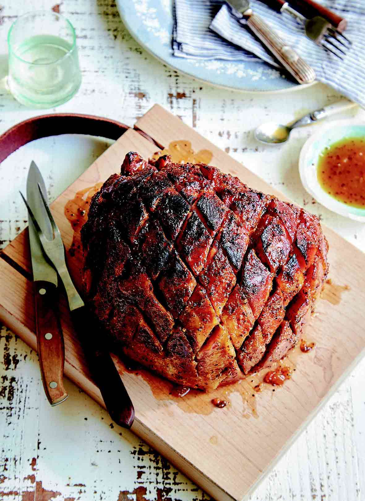 A fully cooked ham with ginger peach glaze on a carving board
