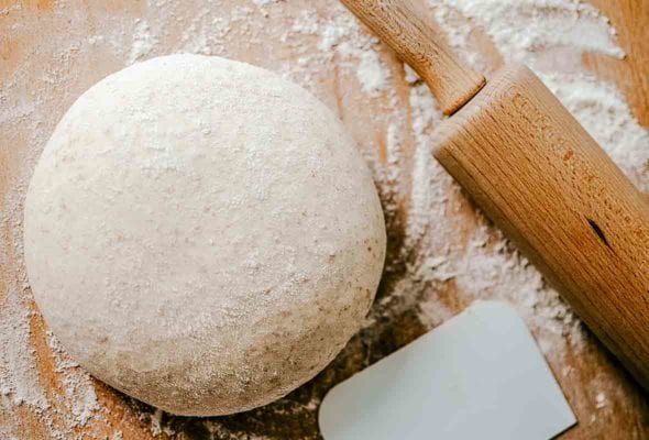 A ball of whole wheat pizza dough on a floured surface