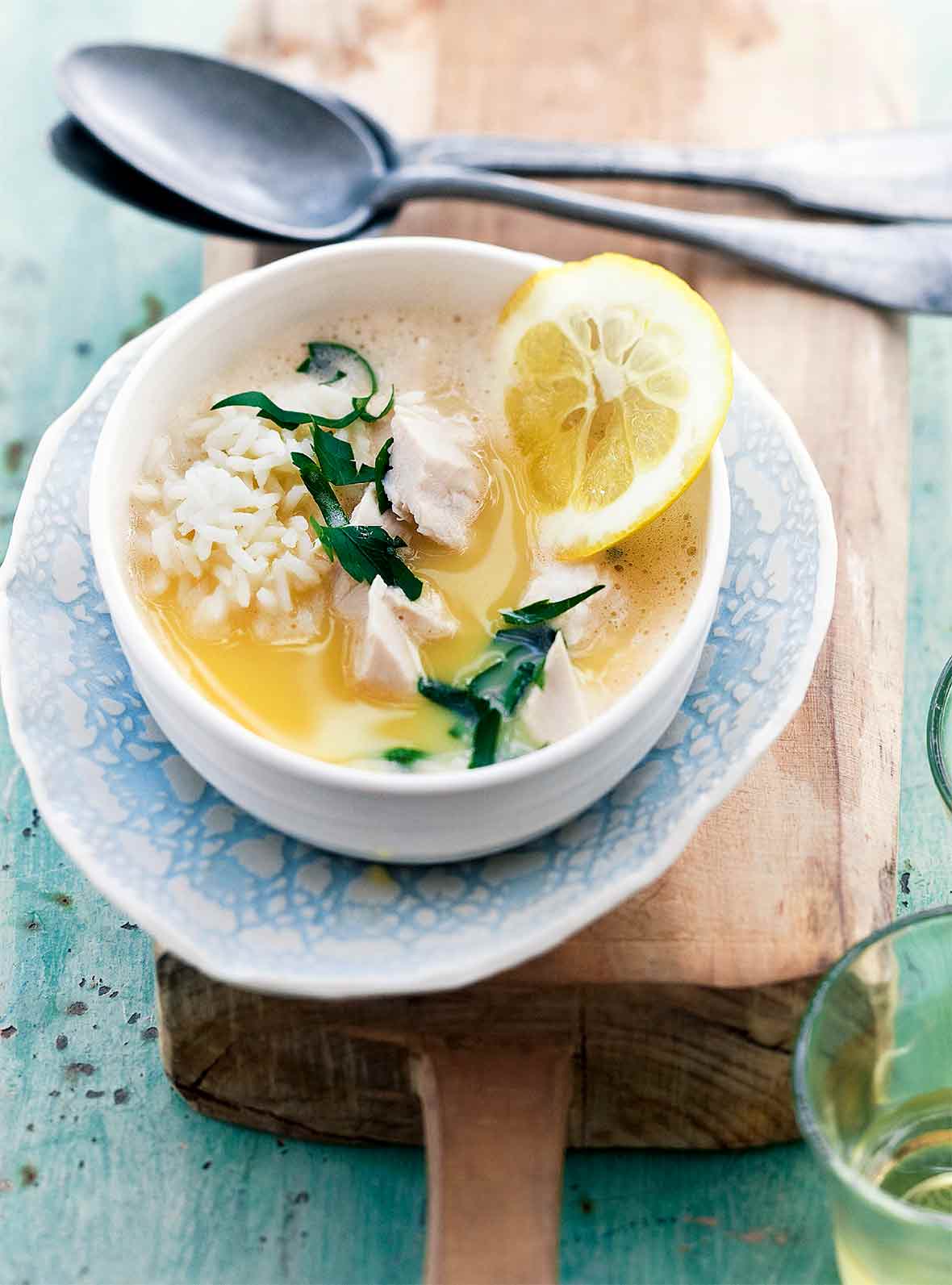 A white and blue bowl filled with healthy avgolemono made with fish, rice, and lemon